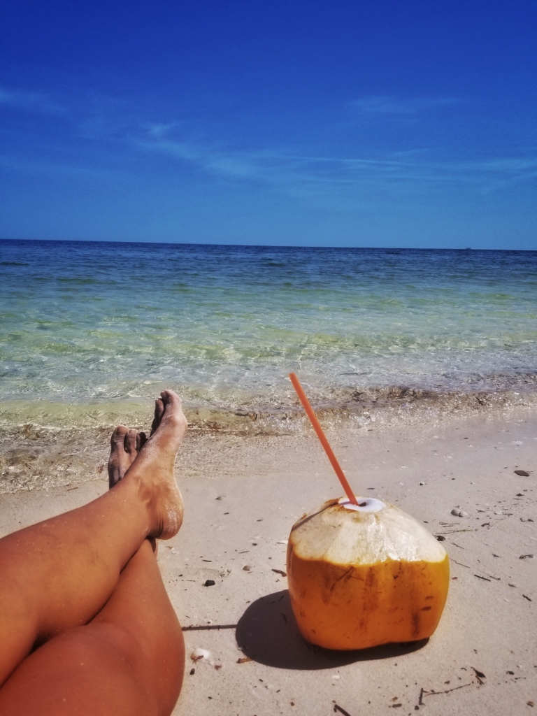 sandy feet coconut drink on the beach